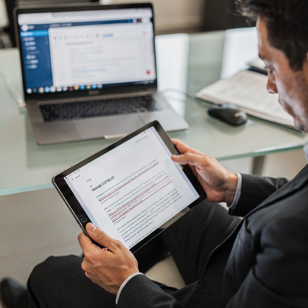 Jurist, der Vertragsredlines auf einem Tablet prüft